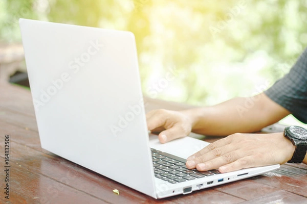 Fototapeta Stock photo :.Closeup image of a hands working and typing on laptop keyboard with blur nature background