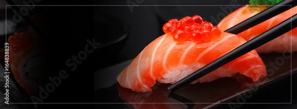 Obraz Kuchnia japońska. Nigiri sushi z łososia pałeczkami na czarnym tle.