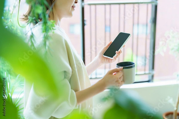 Obraz 部屋でスマートフォンを手にする女性