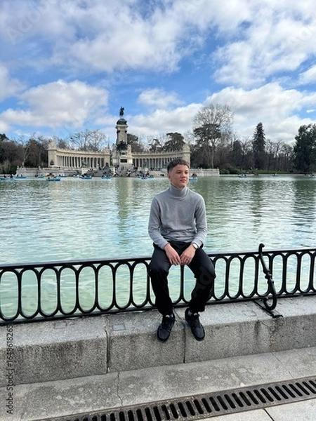 Fototapeta Tourist Gazing Over the Lake : A solitary figure gazes across the serene lake, an awe-inspiring scene where tranquil water and beautiful architecture harmonize under the expansive sky. 