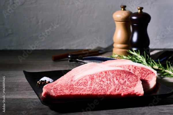Obraz 極上の霜降り和牛ロース肉二枚、黒い皿に盛られた高級生肉と調味料の静物写真