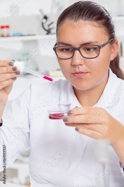 Fototapeta A teenage girl in a school laboratory in chemistry , doing experiments in lab.