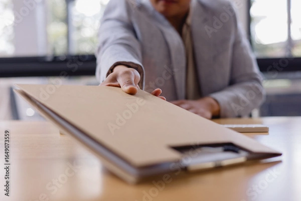 Fototapeta businessman handing over a brown folder across the desk, concept for document delivery, business agreement, contract signing professional office communication.