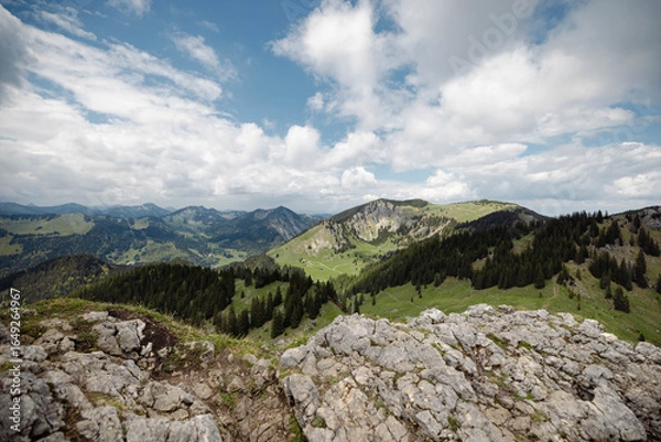 Fototapeta Mountain Panorama with Rocky Foreground and Rolling Green Hills under Cloudy Sky