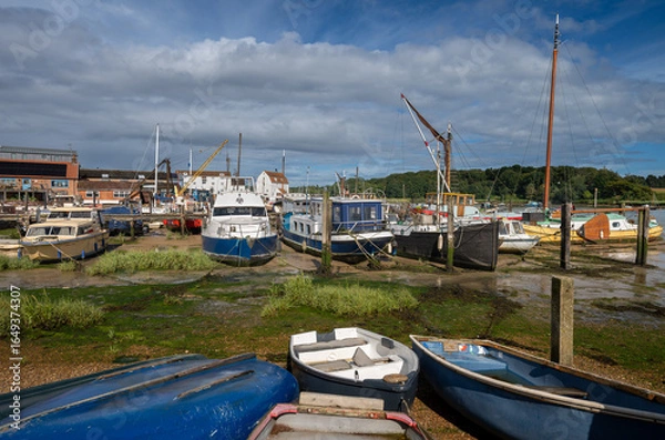 Fototapeta Small boats on a sunny day. View of the quay at low tide on the River Deben in the historic town of Woodbridge in Suffolk, UK.