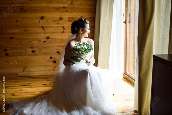 Fototapeta Best wedding morning. Wedding concept - The bride waits for the groom near the window at home