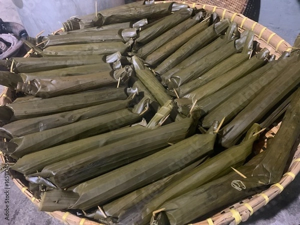 Fototapeta Lontong is a traditional Indonesian dish made from rice that is boiled and compressed in banana leaves, then cut into small cylindrical or round pieces. The texture is firm yet soft, and it has a mild