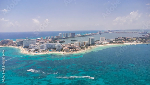 Fototapeta A beautiful blue ocean with a small island in the middle. The island is surrounded by a few buildings and a few boats. Aerial Views of Cancun Hotel zone, Quintana Roo Mexico 