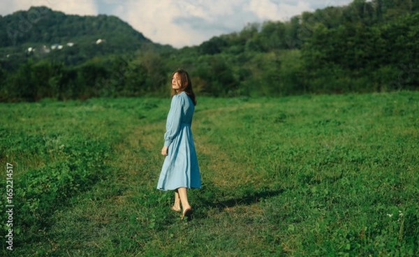 Fototapeta Young Woman Walking on Path in Green Summer Forest, Serene Nature Scene with Sunlight and Tranquility