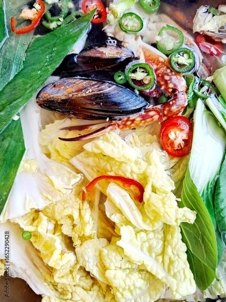Fototapeta Making Korean seafood stew Haemultang  - Stew made of fish, blue crab, sea mussels, and fresh vegetables like Napa cabbage leaves,  big green oinon slices, green and red pepper slices, etc.