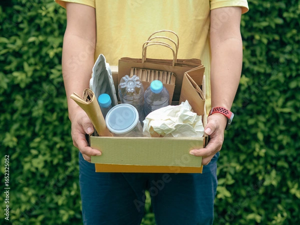 Fototapeta Young man hand holding box of garbage for recycling. Reuse reduce recycle concept.