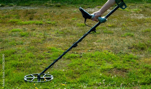 Fototapeta a man walks through a field with a metal detector