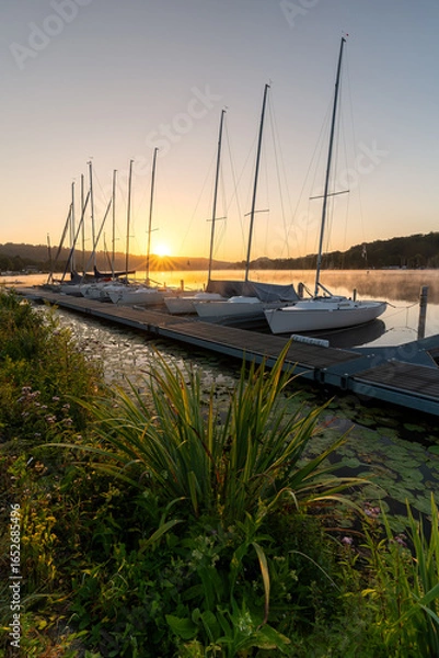 Fototapeta Sailboats in the marina on Lake Baldeneysee in Essen at sunrise. Vertical view