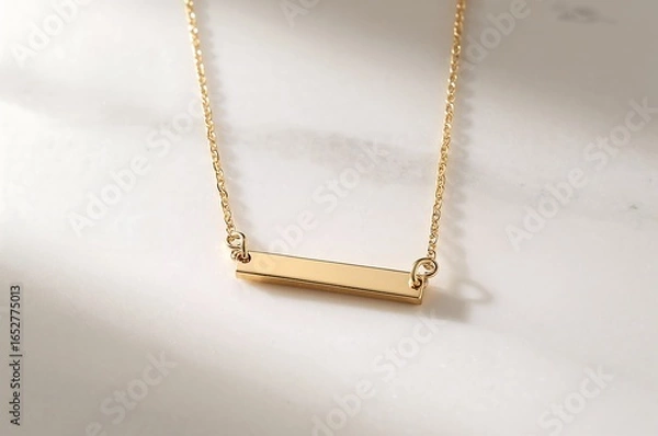 Obraz A close up of a gold bar necklace with a delicate chain on a white surface with soft lighting shown