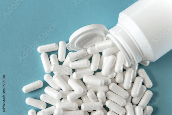 Fototapeta White tabletts or pills on the blue background.
