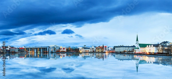Fototapeta Beautiful panorama of the skyline cityscape of Reykjavik, reflected in lake Tjornin at the blue hour in winter