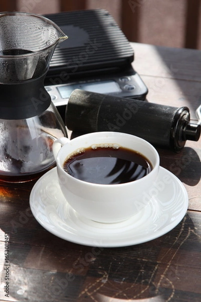 Fototapeta Pour-over filter dripper brewing coffee into glass Alternative coffee brewing method, pure over, teapot on wooden table

