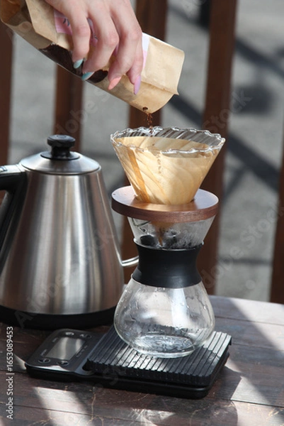 Fototapeta Pour-over filter dripper brewing coffee into glass Alternative coffee brewing method, pure over, teapot on wooden table

