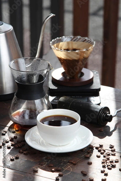 Fototapeta Pour-over filter dripper brewing coffee into glass Alternative coffee brewing method, pure over, teapot on wooden table

