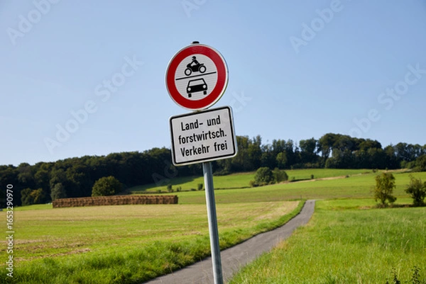 Fototapeta country path between fields with german traffic sign that it is closed for cars and motor bikes