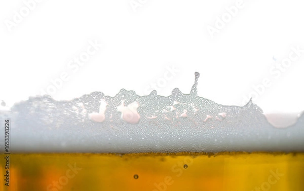 Fototapeta Beer foam close-up with bubbles on golden liquid