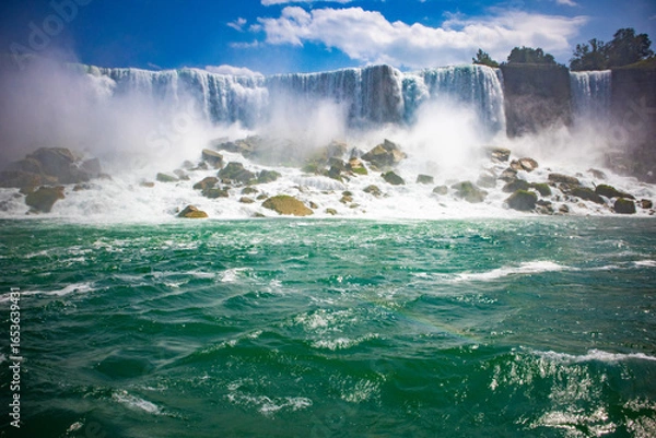 Fototapeta The gushing turquoise water from the Niagara falls with blue sky and white clouds the beautify scenry of nature