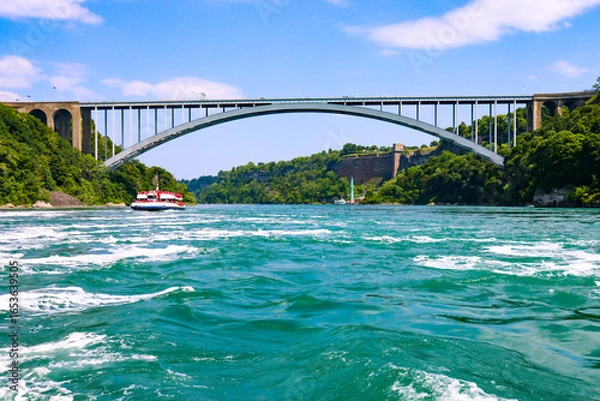 Fototapeta The gushing turquoise water from the Niagara falls with blue sky and white clouds the beautify scenry of nature