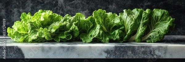 Obraz Fresh, vibrant green leafy vegetables arranged on a marble surface against a dark background