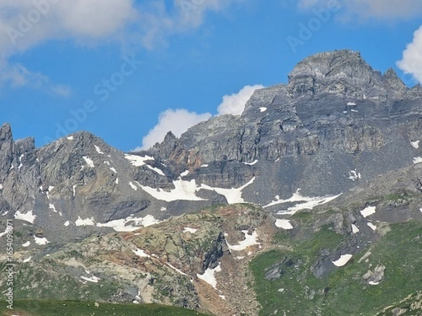 Fototapeta La Thuile, Val D'Aosta, July 02 2025: Panoramic view to the alps, beautiful green landscape reflected in a small natural lake. Beautiful blue sky with some clouds. Mountains with a little snow. Aerial