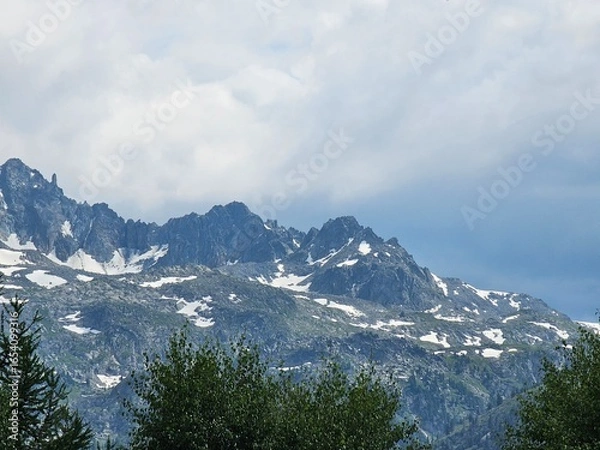 Fototapeta La Thuile, Val D'Aosta, July 02 2025: Panoramic view to the alps, beautiful green landscape reflected in a small natural lake. Beautiful blue sky with some clouds. Mountains with a little snow. Aerial