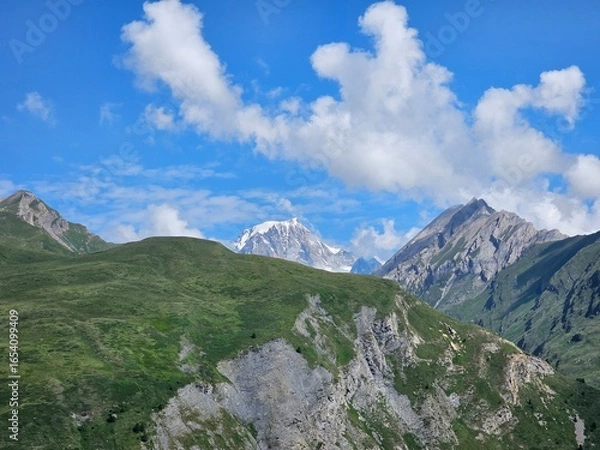 Fototapeta La Thuile, Val D'Aosta, July 02 2025: Panoramic view to the alps, beautiful green landscape reflected in a small natural lake. Beautiful blue sky with some clouds. Mountains with a little snow. Aerial