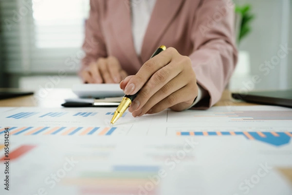 Fototapeta A professional businesswoman reviews financial documents using a calculator, pen, and laptop in the office, analyzing reports, charts, and graphs to manage budget, expenses, investment, and strategic 