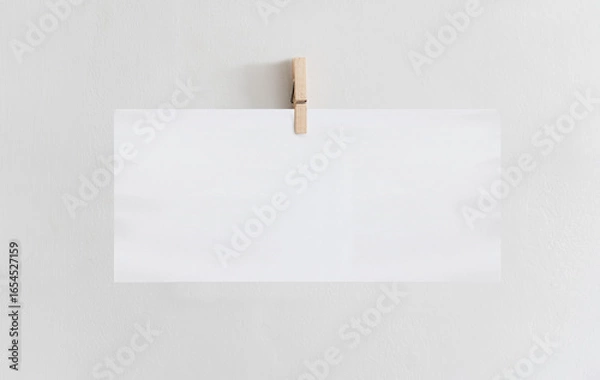 Fototapeta White rectangle paper, wooden clip on white wall, empty copy space for backgrounds