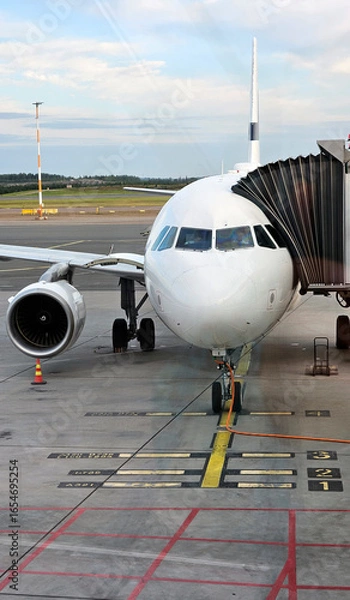 Fototapeta Airplane with passenger jet bridge attached. View from the airport window