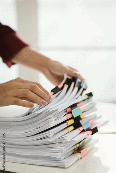 Fototapeta A woman in a red shirt is handling a large number of documents and files, symbolizing office work, documentation, organization, management, deadlines, workloads, bureaucracy, and business responsibili