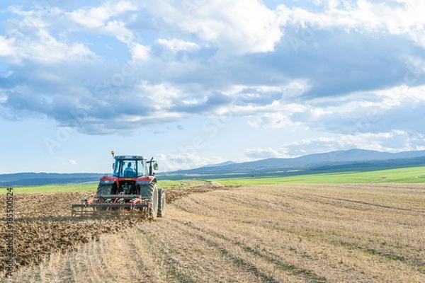 Obraz agricultural machinery in the foreground carrying out work in the field.