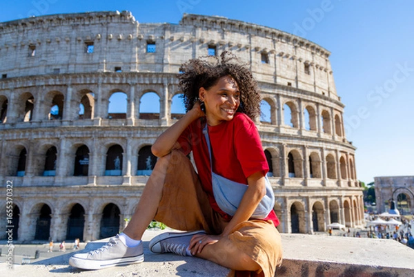 Fototapeta A joyful traveler poses cheerfully against the magnificent backdrop of the iconic Colosseum in Rome, capturing the true spirit of adventure on a beautifully sunny day full of possibilities