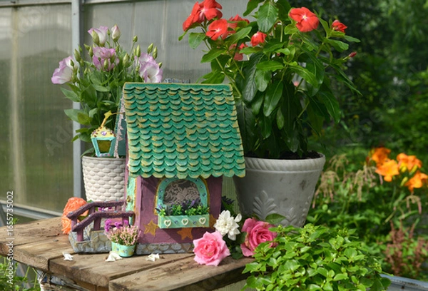 Fototapeta Cute fairy doll house with potted flowers in the garden greenhouse. Lovely miniature for greeting cards, wedding or birthday concept, real estate, downsizing, home ownership. Vintage background