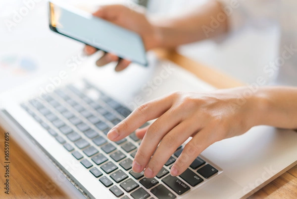 Fototapeta Business woman hand with Financial charts and mobile phone over laptop on the table .