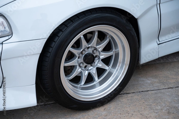Fototapeta Detail of a multi-spoke alloy front wheel on a modified classic Japanese sports car, showcasing the clean, polished finish and aftermarket widebody modifications.