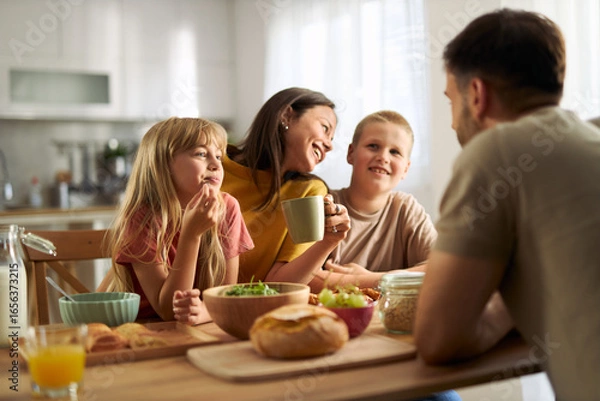 Fototapeta Happy family enjoying while having breakfast in dining room.
