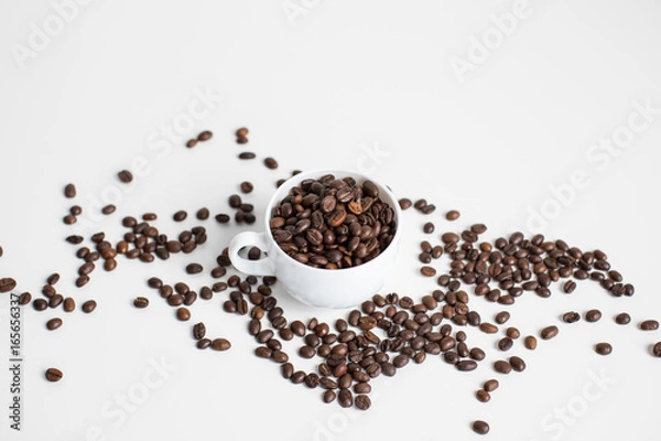 Obraz white cup with scattered coffee beans, isolated on white