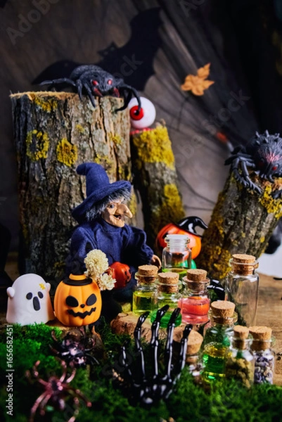 Fototapeta halloween, dark forest, clearing, witch sits on a tree stump in her cozy shelter with spiders, a ghost, an eye, pumpkins and conjures over jars of potions on the eve of All Saints Day, selective focus
