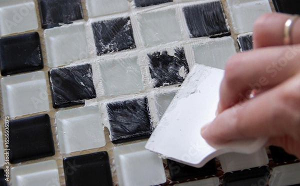 Fototapeta hand spreading grout on black and white small tiles