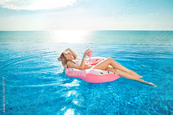 Fototapeta Summer Vacation. Woman in bikini on the inflatable donut mattress in the SPA swimming pool.