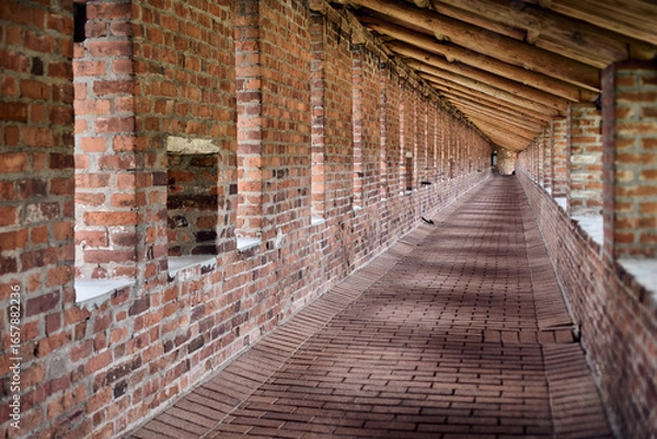 Fototapeta Long brick corridor of Nizhny Novgorod kremlin, showcasing detailed masonry and repetitive arches. Soft, ambient lighting creates warm and historical atmosphere, with perspective drawing into distance