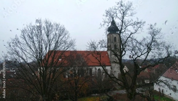 Fototapeta A Serene Church Amidst Bare Trees And Raindrops, Capturing The Tranquil Beauty Of European Architecture On A Cloudy Day, A Visual Masterpiece. With Comprehensive Details And Informative