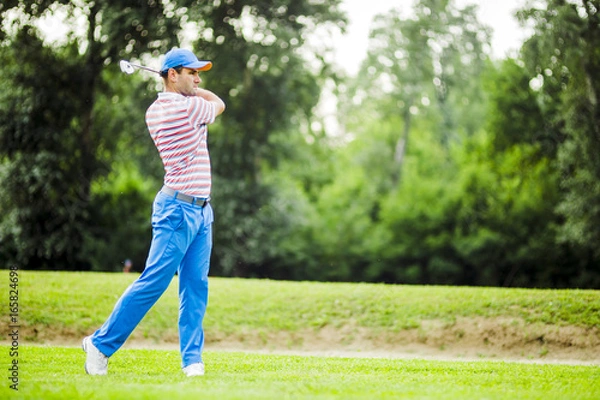 Fototapeta Golfer practicing and concentrating before and after shot
