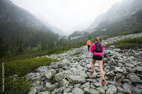 Obraz woman hiking on high mountains  outdoor track in bad weather with fog and rain
