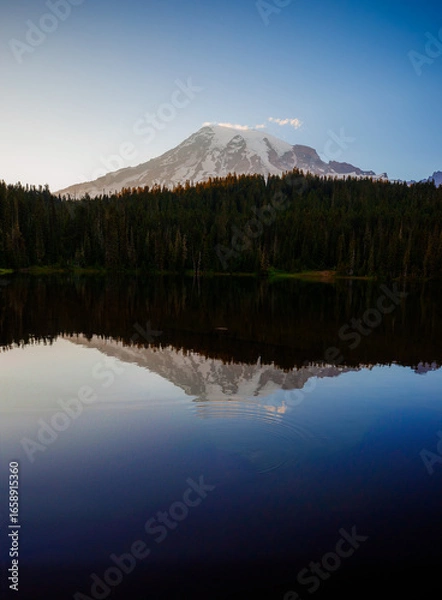 Fototapeta Calm Reflection Lake with mirror-like surface reflecting surrounding mountains and trees. Serene nature scene perfect for outdoor and landscape photography.